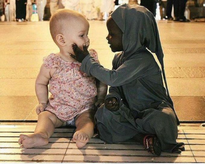 photo d'un.e? enfant la peau noire carressant la joue d'une enfant la peau blanche